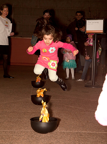 fire jumping at nowruz at the freer and sackler - a girl jumps over a fake fire